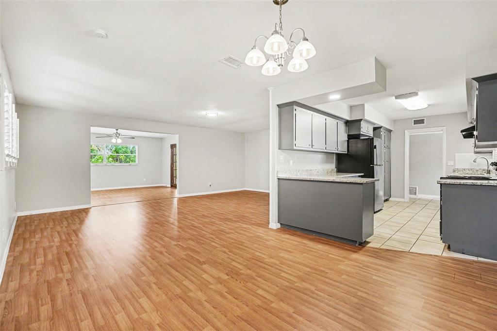 A living room with wood-look flooring flows into a kitchen featuring grey cabinets and counters — 714 COULTER PLACE, BRANDON, FL