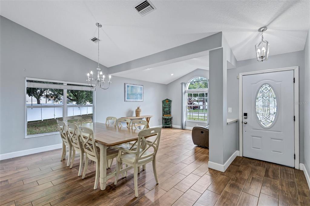 A dining room with wood-look tile floors, a chandelier, and an adjacent entryway with door — 4909 6TH AVENUE E, BRADENTON, FL