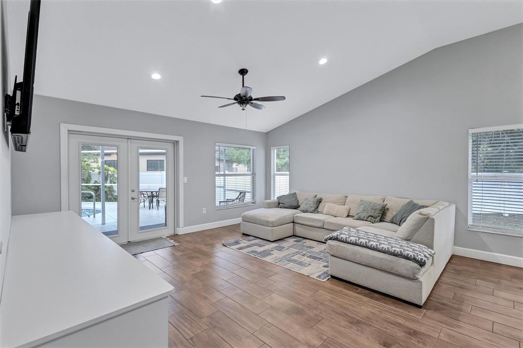 A living room with light gray walls, wood-look tile flooring, and a large sectional sofa — 4909 6TH AVENUE E, BRADENTON, FL