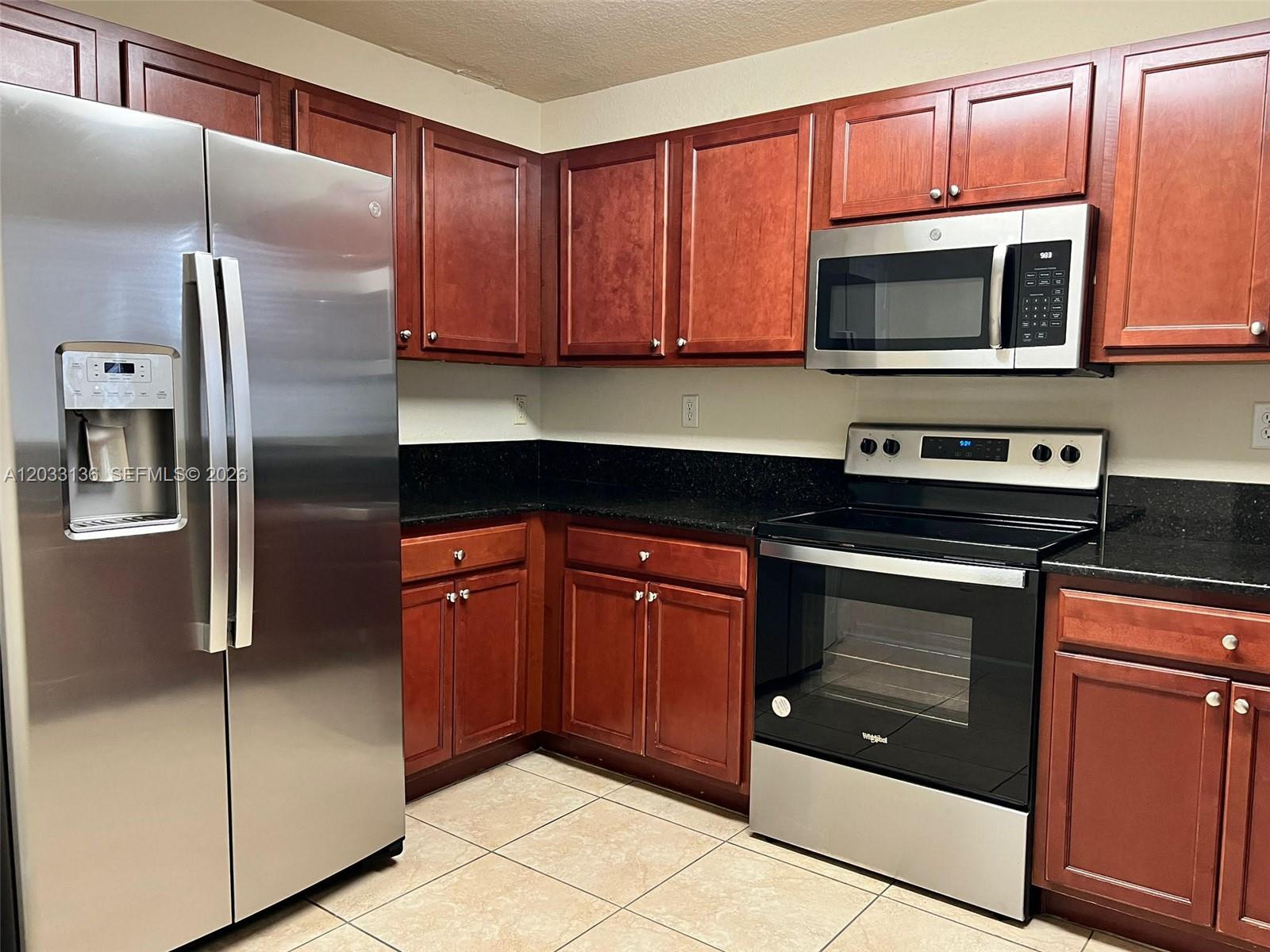 A kitchen features cherry wood cabinets, black granite countertops, and stainless steel appliances — 11503 NW 89th St # 223, Doral FL 33178, DORAL, FL