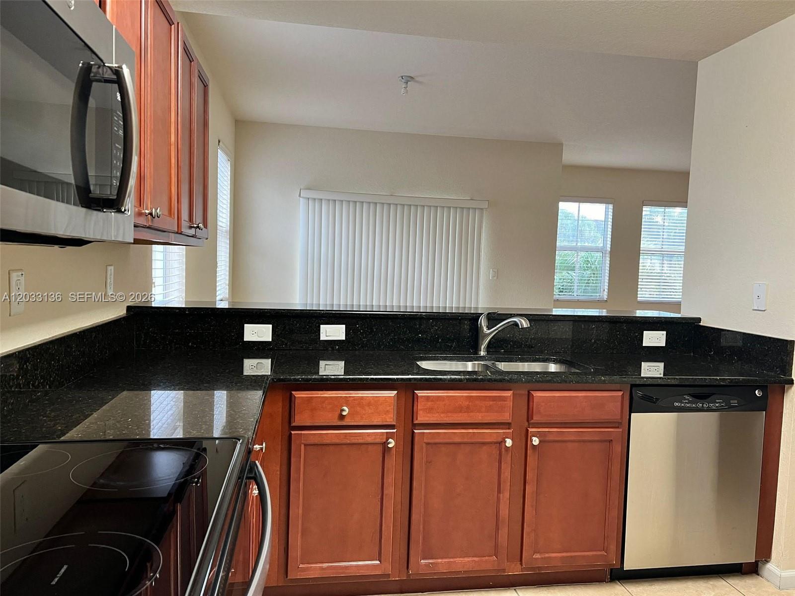A kitchen features dark wood cabinets, black granite countertops, and stainless steel appliances — 11503 NW 89th St # 223, Doral FL 33178, DORAL, FL