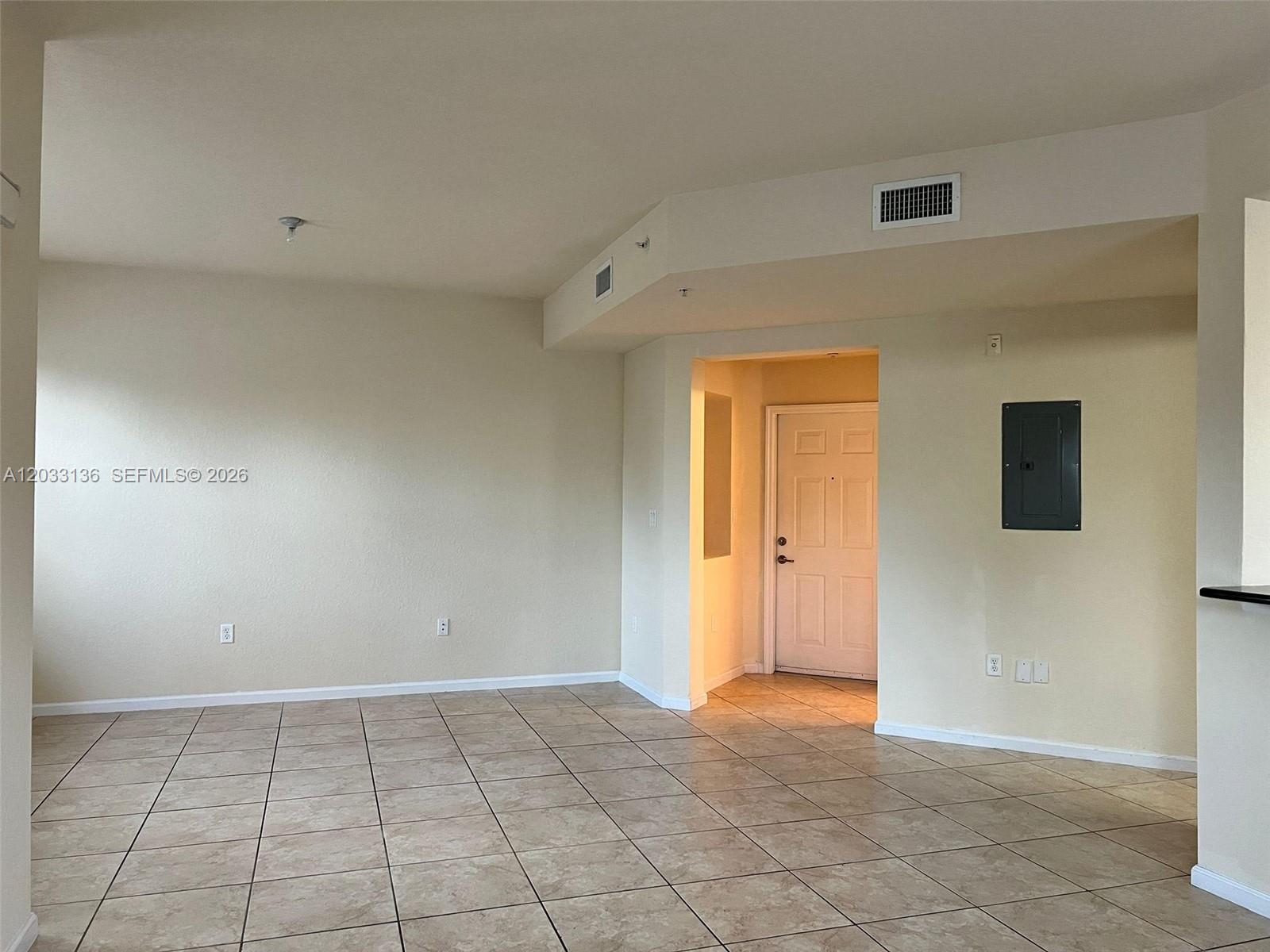 An empty room features beige walls, tiled flooring, an entryway, and an electrical panel — 11503 NW 89th St # 223, Doral FL 33178, DORAL, FL