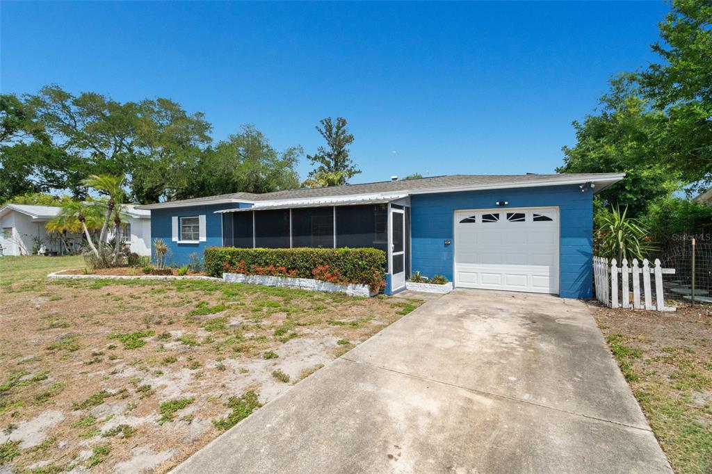 A blue single-story house with a white garage door and a screened-in front porch — 2027 E VALENCIA WAY E, CLEARWATER, FL