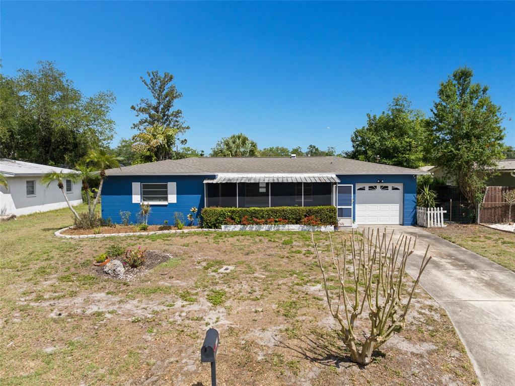 A blue single-story house with a screened-in porch, a one-car garage, and a front yard — 2027 E VALENCIA WAY E, CLEARWATER, FL