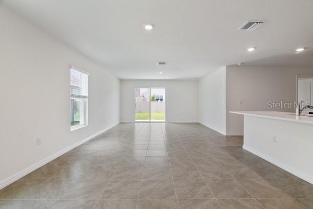 An open-concept living area features light-colored tile flooring, white walls, and a sliding glass door — 8686 SW 44TH TERRACE, OCALA, FL