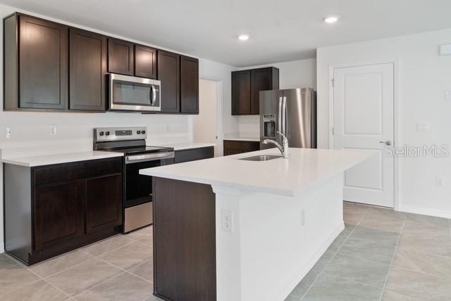A kitchen features dark wood cabinets, stainless steel appliances, and a white kitchen island — 8686 SW 44TH TERRACE, OCALA, FL