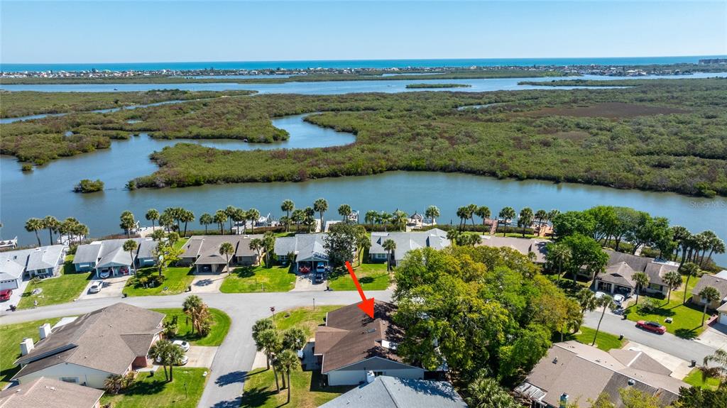 An aerial view shows a residential neighborhood with houses near a bay and mangroves — 1402 PORTOBELLO DRIVE, PORT ORANGE, FL