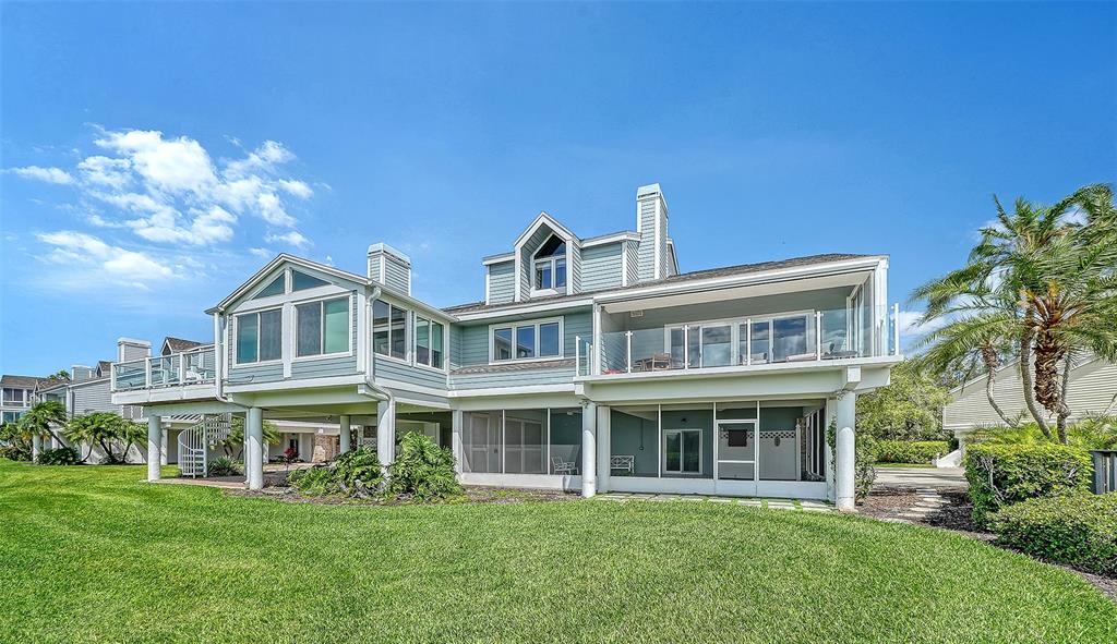 The rear exterior of a multi-story house features a screened-in patio and an upper balcony — 11 TIDY ISLAND BOULEVARD UNIT 11, BRADENTON, FL