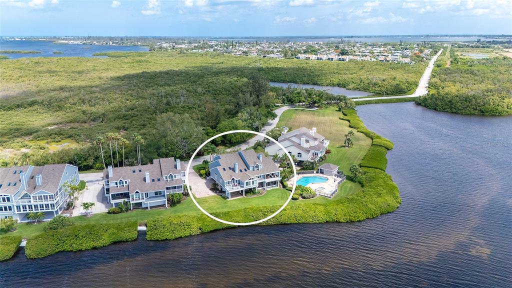 An aerial view shows a waterfront house with a pool surrounded by lush vegetation — 11 TIDY ISLAND BOULEVARD UNIT 11, BRADENTON, FL