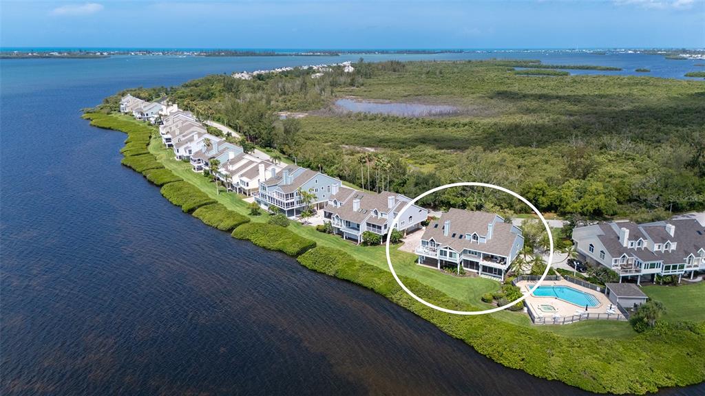 An aerial view shows a multi-story waterfront house with a pool and surrounding vegetation — 11 TIDY ISLAND BOULEVARD UNIT 11, BRADENTON, FL