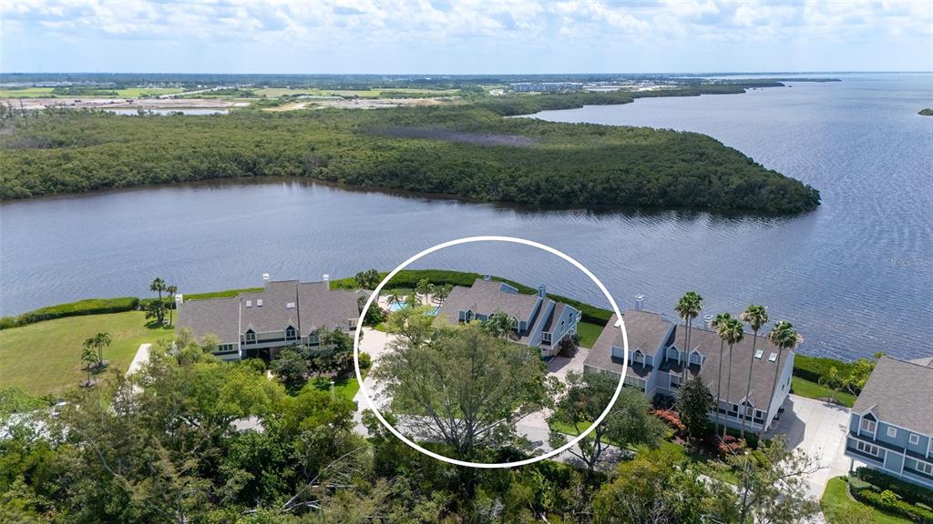 An aerial view shows three multi-story residential buildings situated along a waterfront with dense vegetation — 11 TIDY ISLAND BOULEVARD UNIT 11, BRADENTON, FL