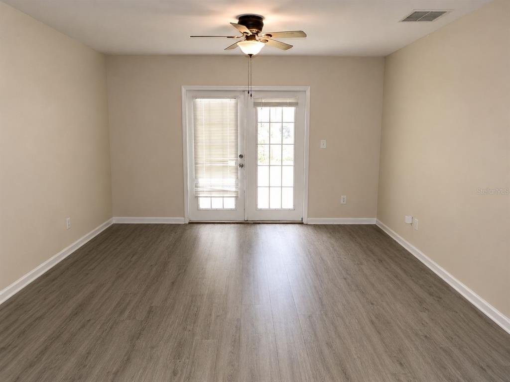 An empty room with light-colored walls, wood-look flooring, a ceiling fan, and glass-paned double doors — 901 SW PECAN STREET, KEYSTONE HEIGHTS, FL