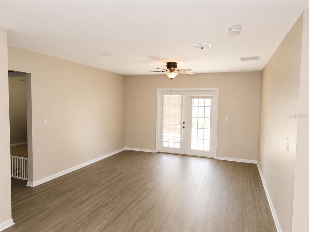 An empty room with light-colored walls, wood-look flooring, a ceiling fan, and glass patio doors — 901 SW PECAN STREET, KEYSTONE HEIGHTS, FL