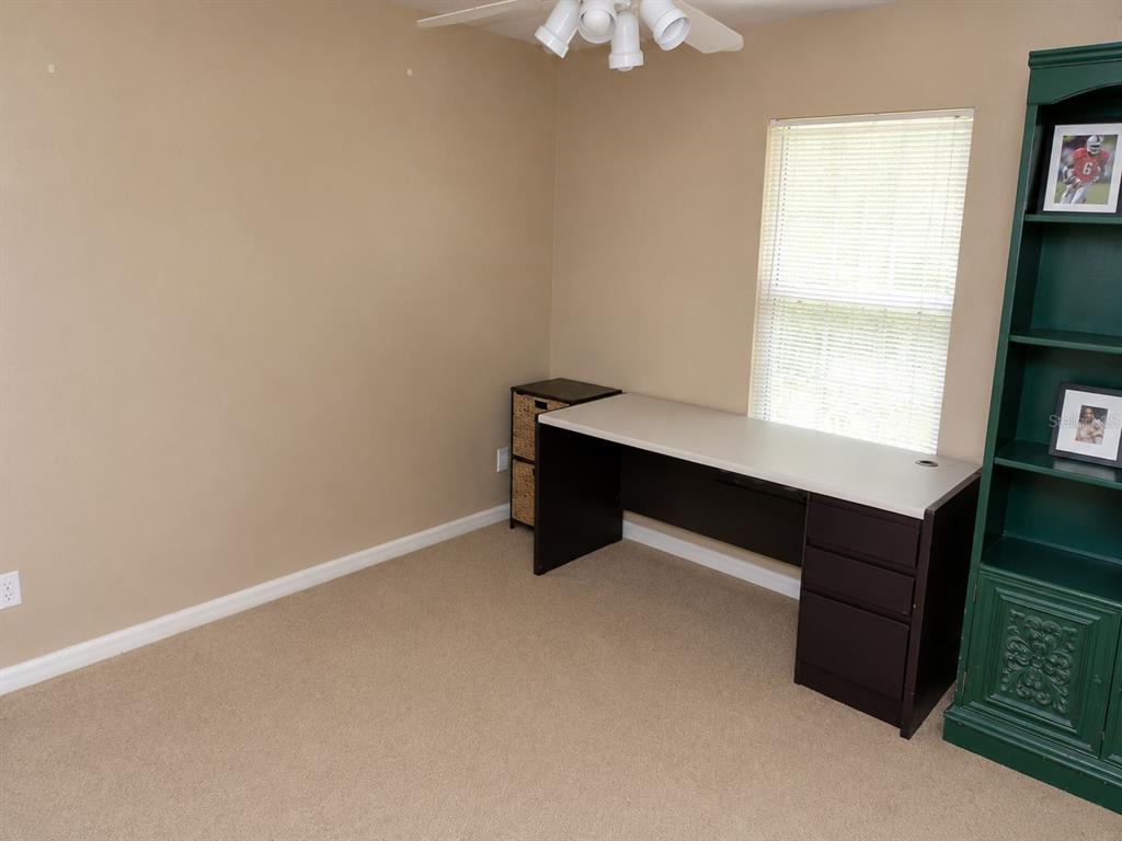 A home office features a desk, a green bookshelf, and a window with blinds — 901 SW PECAN STREET, KEYSTONE HEIGHTS, FL