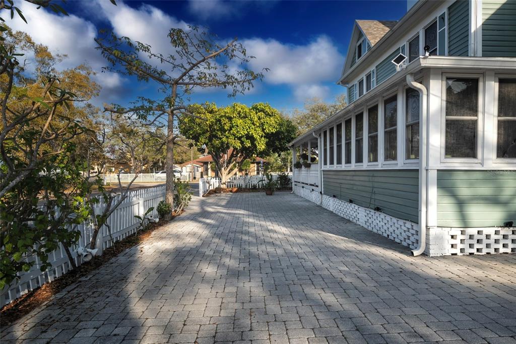 A paved driveway runs alongside a light green house with a white picket fence — 304 15TH STREET W, BRADENTON, FL