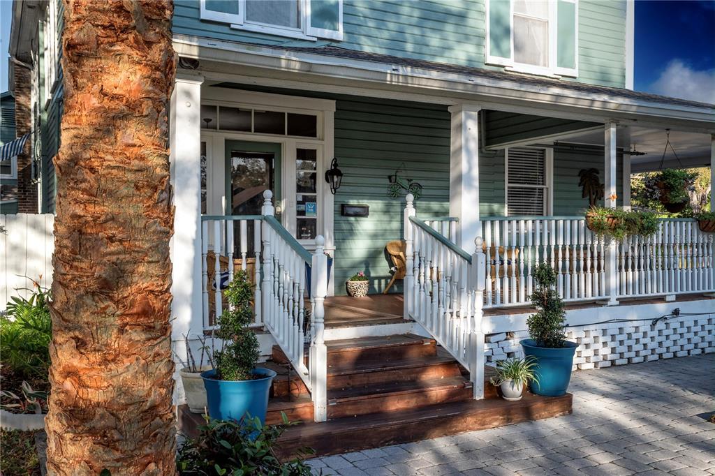 A wooden staircase leads to the covered front porch of a green-sided house — 304 15TH STREET W, BRADENTON, FL