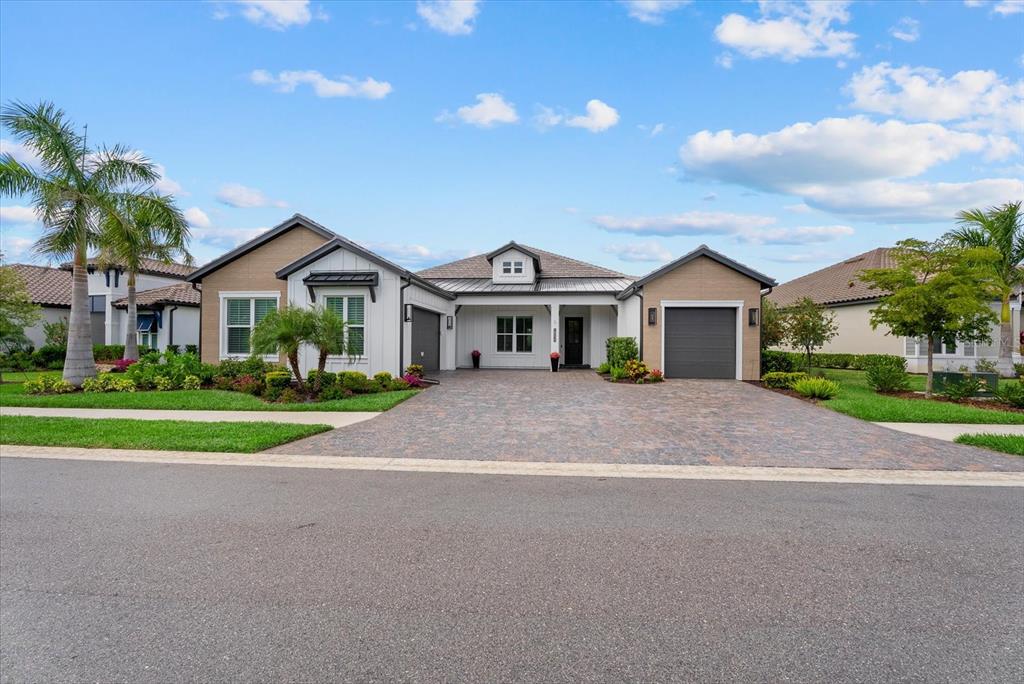 A modern house exterior features a two-car garage, a single-car garage, and a paved driveway — 18035 HOME RUN DRIVE, VENICE, FL