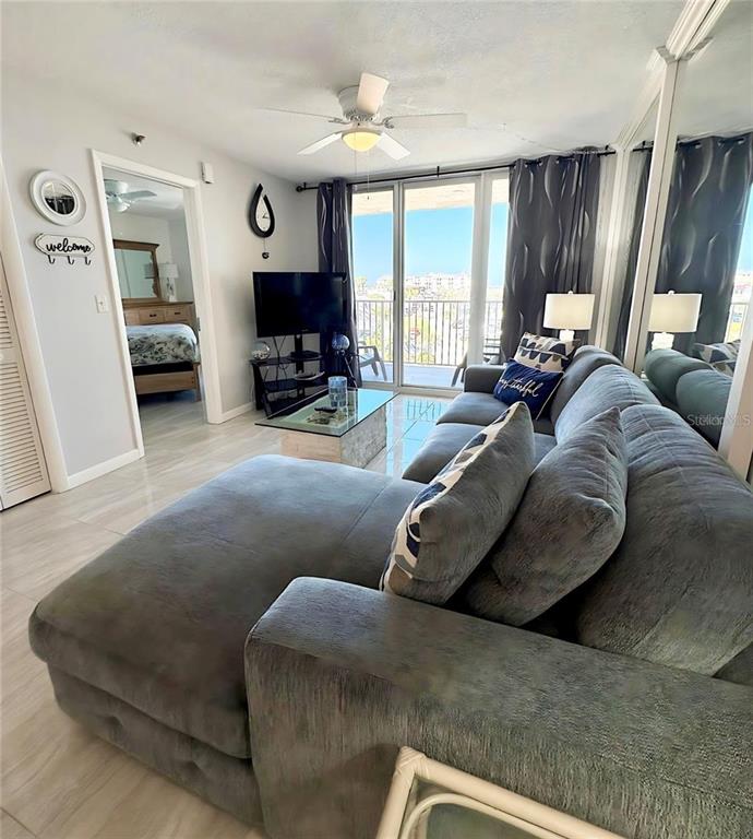 A living room features a gray sectional sofa, a glass coffee table, and a balcony view — 421 S ATLANTIC AVENUE UNIT 409, NEW SMYRNA BEACH, FL