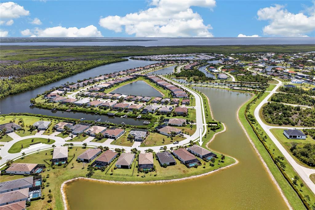 An aerial view shows a residential neighborhood with houses situated along a winding canal — 14605 PONCE DE LEON TRAIL, PORT CHARLOTTE, FL