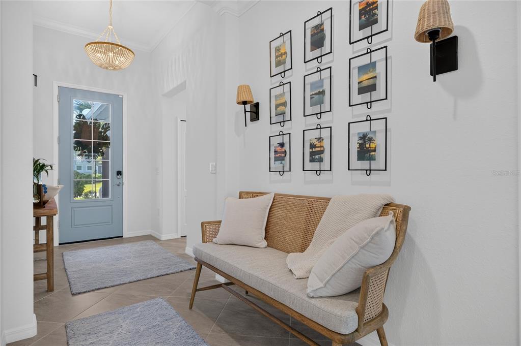 A light-filled entryway features a blue front door, a cane bench, and a gallery wall — 14605 PONCE DE LEON TRAIL, PORT CHARLOTTE, FL