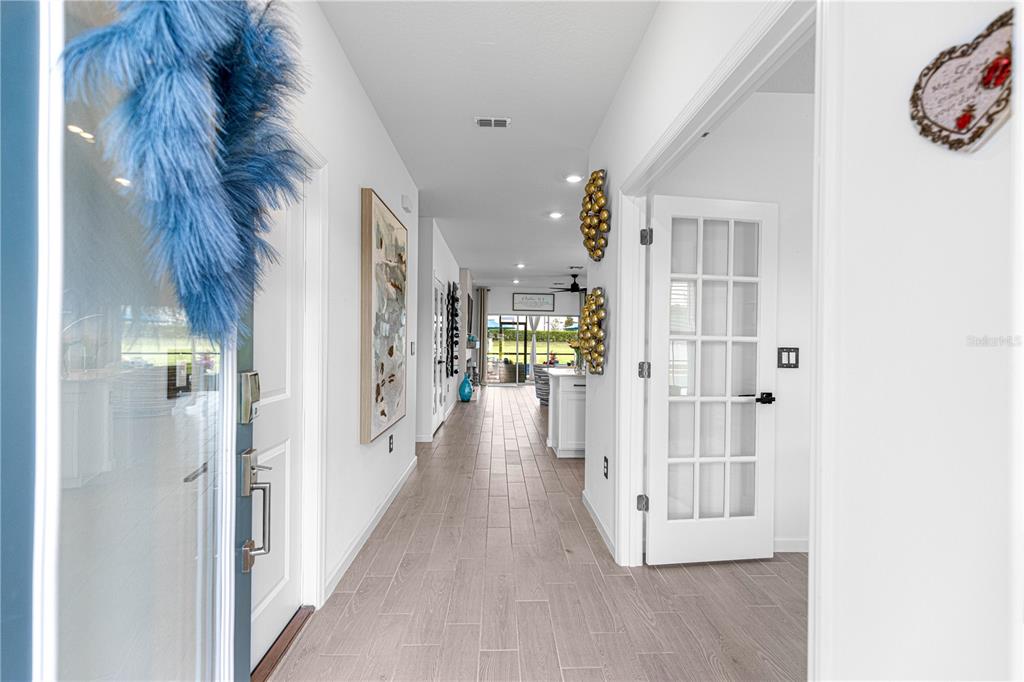 A bright entryway leads down a tiled hallway toward an open living area with glass doors — 4417 NW 14TH LOOP, OCALA, FL
