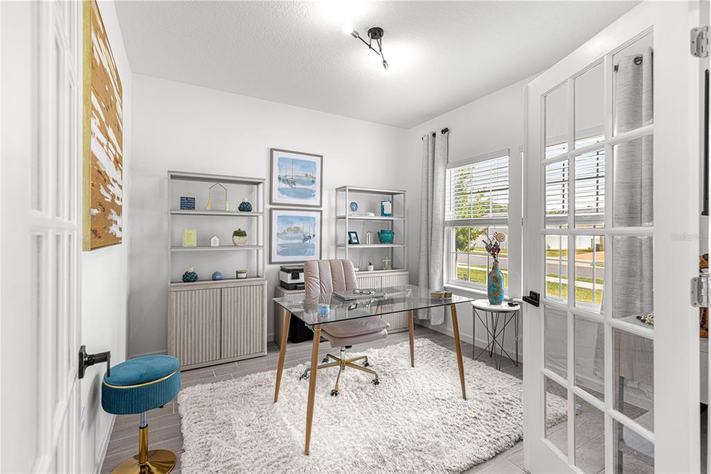 A home office features a glass desk, two bookshelves, a rug, and French doors — 4417 NW 14TH LOOP, OCALA, FL