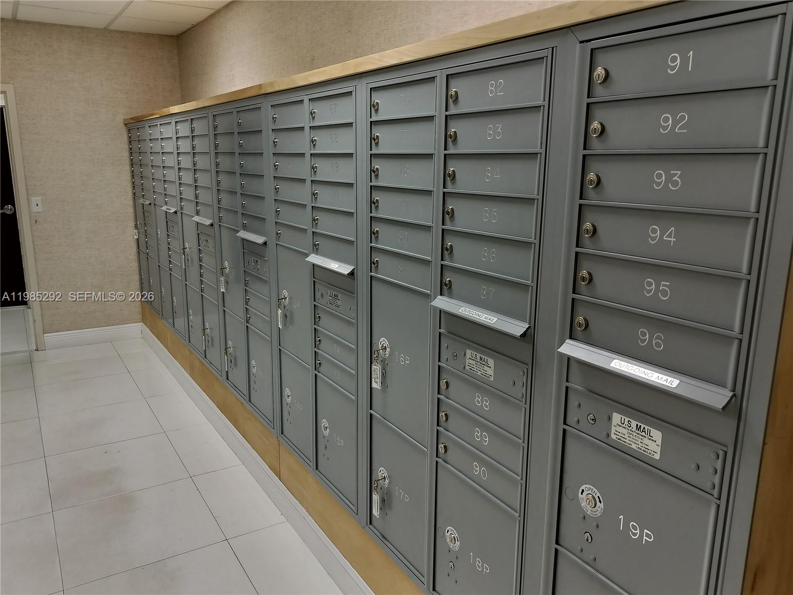 A wall of gray metal mailboxes with numbered slots is installed in a tiled room — 12550 Biscayne Blvd # 213, North Miami FL 33181, NORTH MIAMI, FL