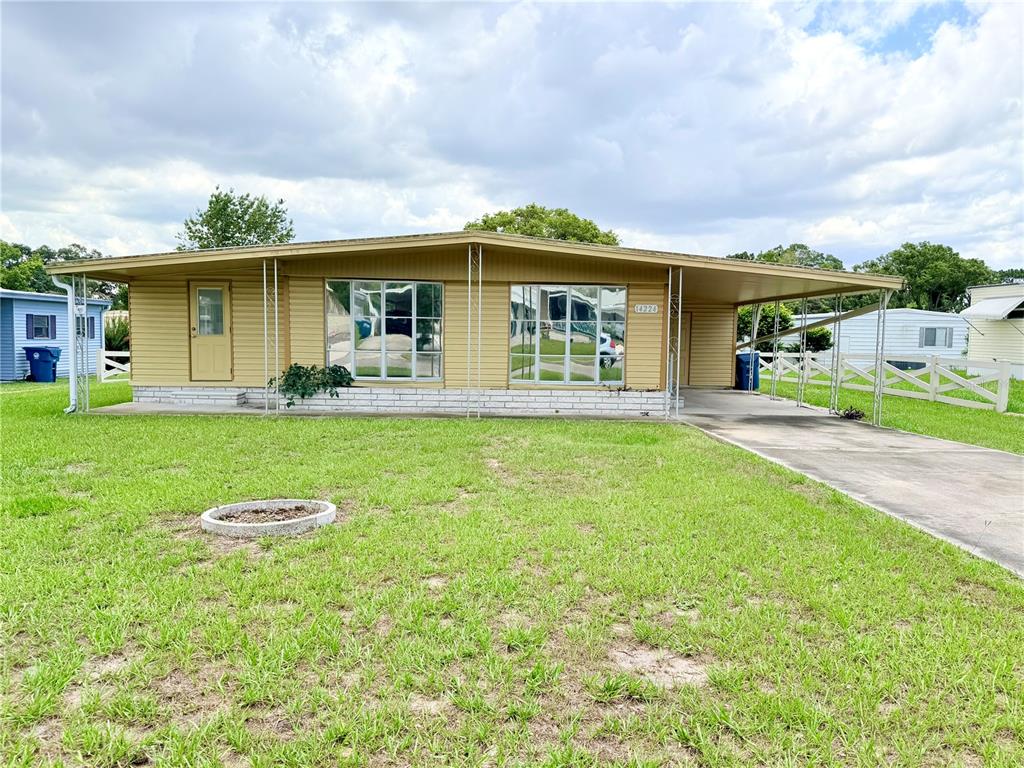 A single-story mobile home with yellow siding, a front porch, and an attached carport — 14224 SANDHURST STREET, BROOKSVILLE, FL