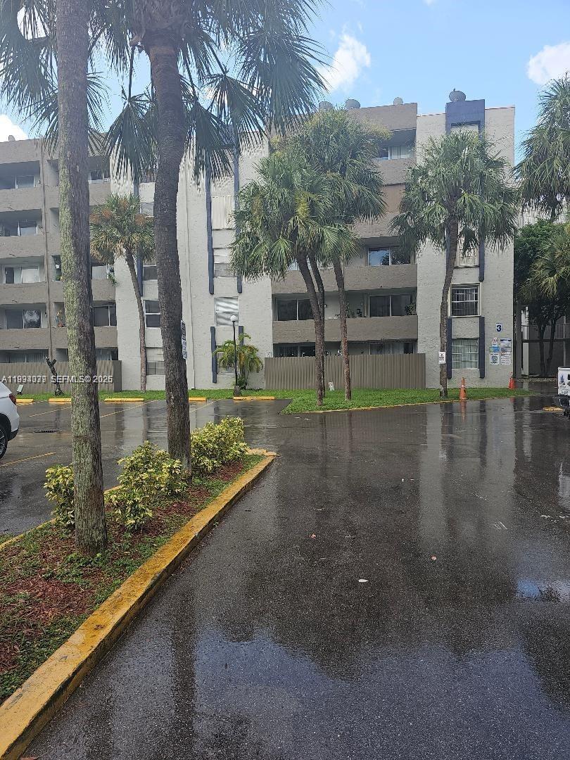 A multi-story apartment building with palm trees and a wet parking lot in front — 10000 NW 80th Ct # 2415, Hialeah Gardens FL 33016, HIALEAH GARDENS, FL