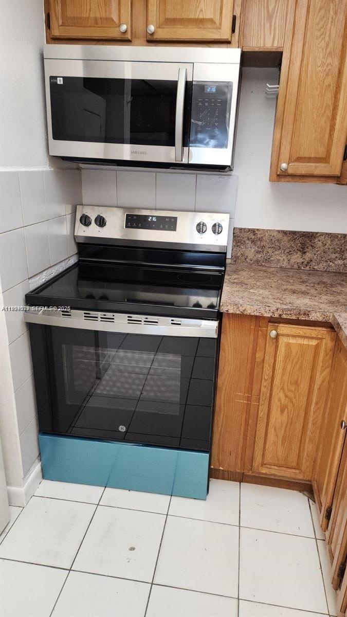 A kitchen features a stainless steel microwave, a black electric range, and wood cabinets — 10000 NW 80th Ct # 2415, Hialeah Gardens FL 33016, HIALEAH GARDENS, FL