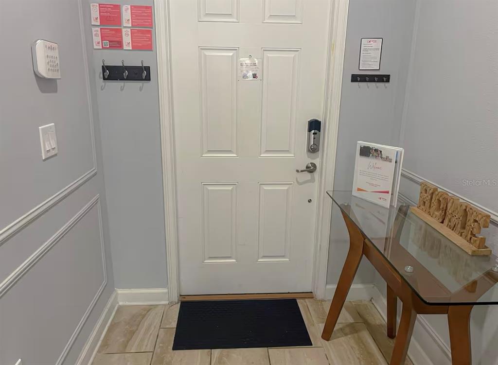 A foyer features a white door, a glass-topped console table, and wall-mounted coat hooks — 3052 GATSBY STREET, KISSIMMEE, FL