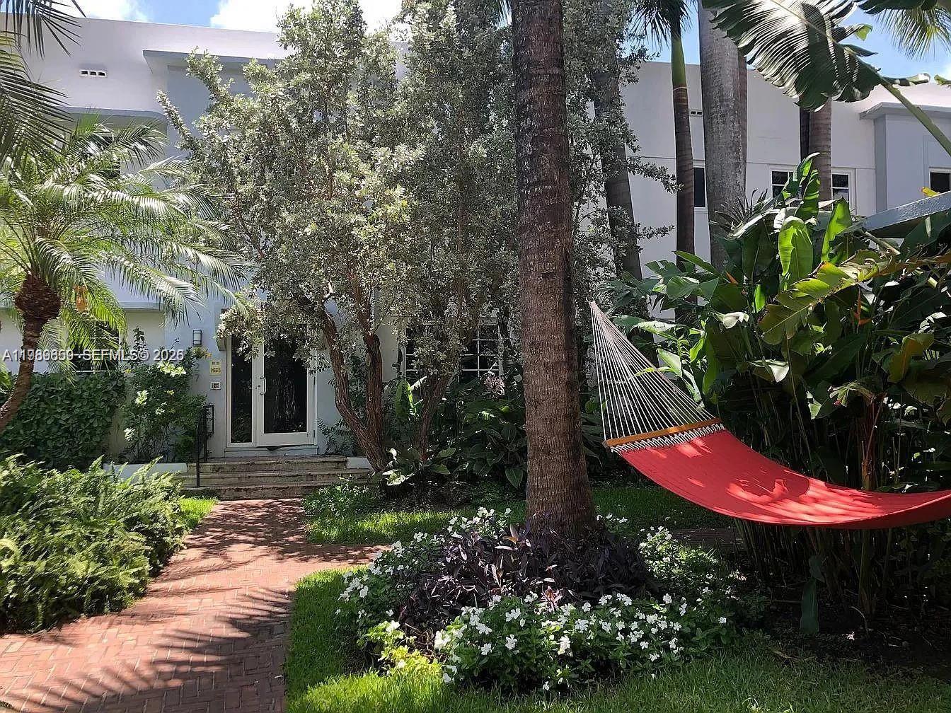 A red hammock hangs in a lush garden in front of a white building — 727 14th Pl # 1, Miami Beach FL 33139, MIAMI BEACH, FL