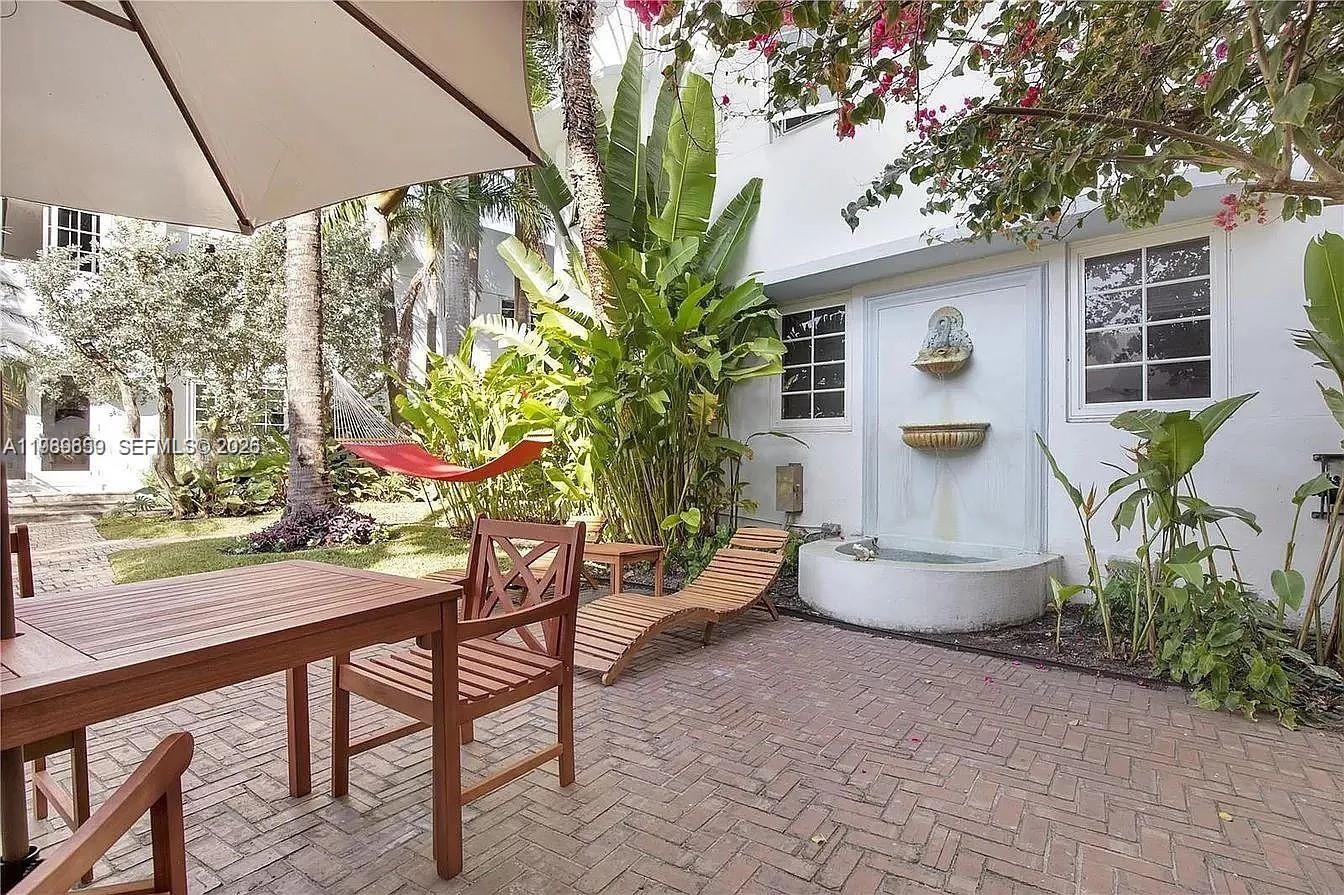 A brick patio features a wooden table, lounge chairs, a fountain, and a red hammock — 727 14th Pl # 1, Miami Beach FL 33139, MIAMI BEACH, FL