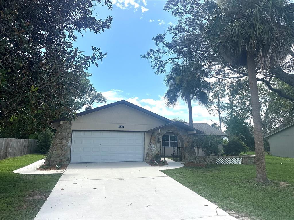 A single-story house with a stone-accented facade, a two-car garage, and a palm tree — 2378 CANFIELD DRIVE, SPRING HILL, FL