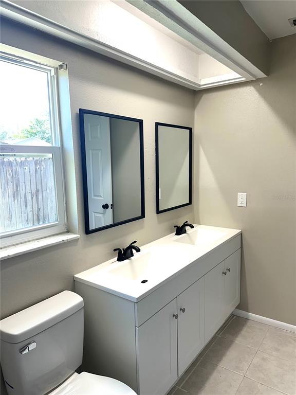 A bathroom features a double-sink vanity with black faucets, two rectangular mirrors, and a toilet — 2378 CANFIELD DRIVE, SPRING HILL, FL