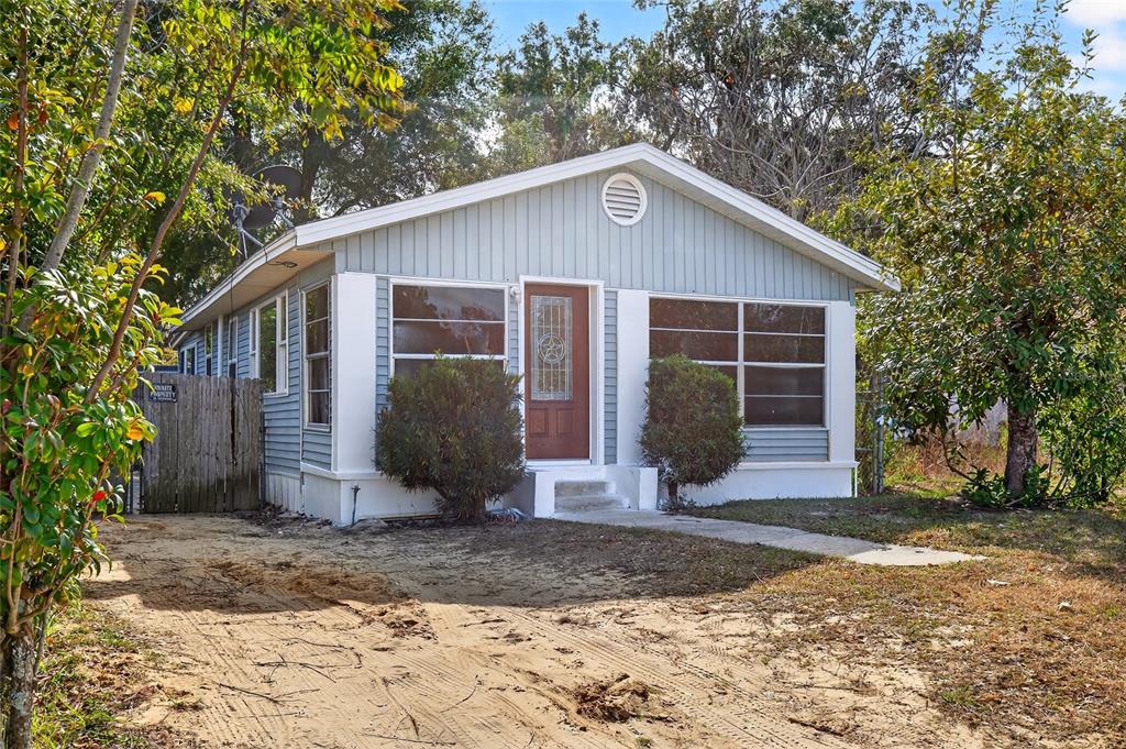 A light blue single-story house with a brown front door and a sandy driveway — 1110 SW FORT KING STREET, OCALA, FL