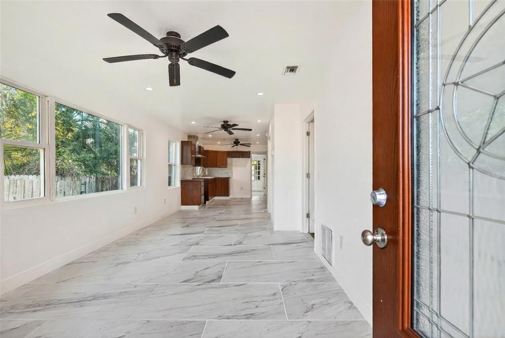 A view from an entryway into a long room with marble-look tile and ceiling fans — 1110 SW FORT KING STREET, OCALA, FL