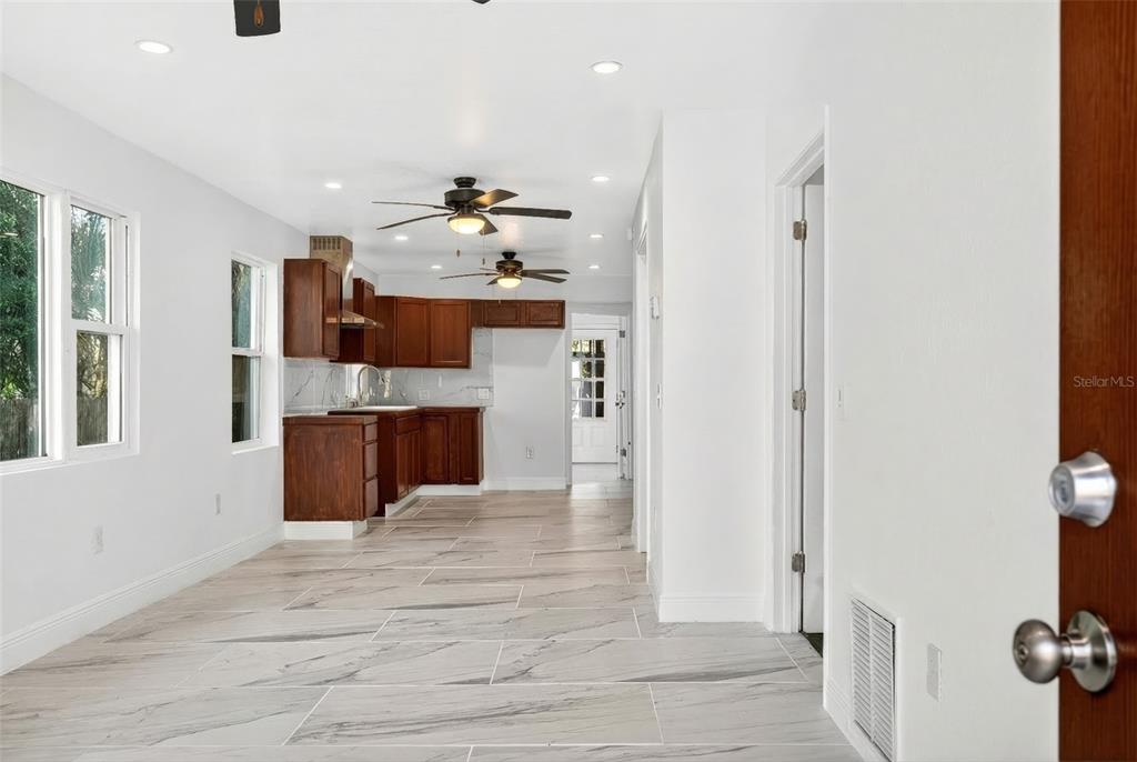 A kitchen with wood cabinets and marble-look tile flooring viewed from an adjacent room — 1110 SW FORT KING STREET, OCALA, FL