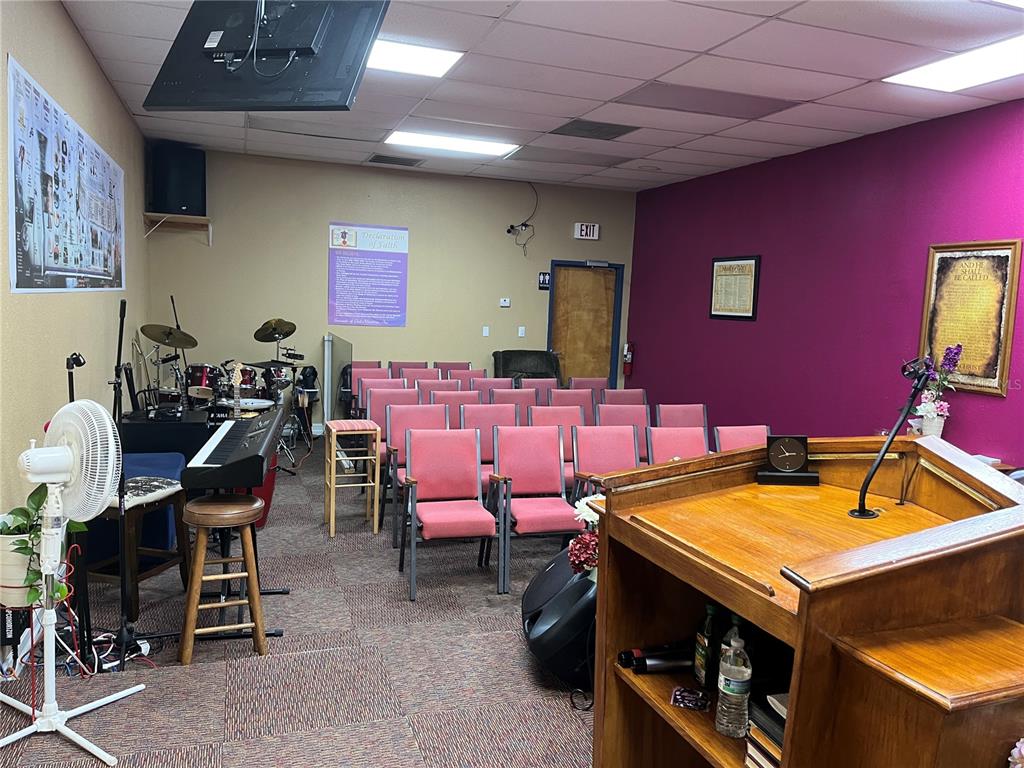 A small church sanctuary features rows of pink chairs, a wooden pulpit, and musical instruments — 1706 E SEMORAN BOULEVARD UNIT 116, APOPKA, FL