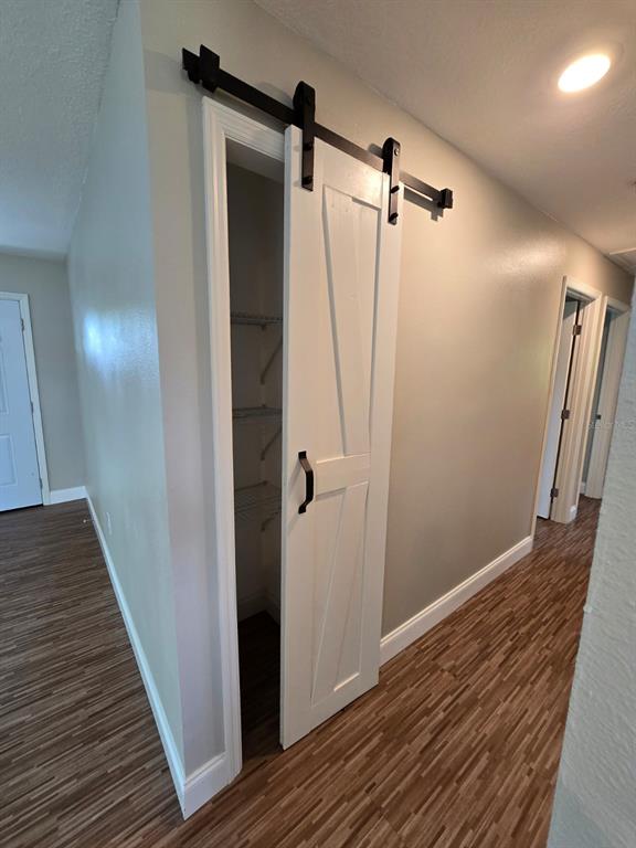 A white barn door on a black track covers a closet in a hallway — 11548 MISSOURI STREET, LEESBURG, FL
