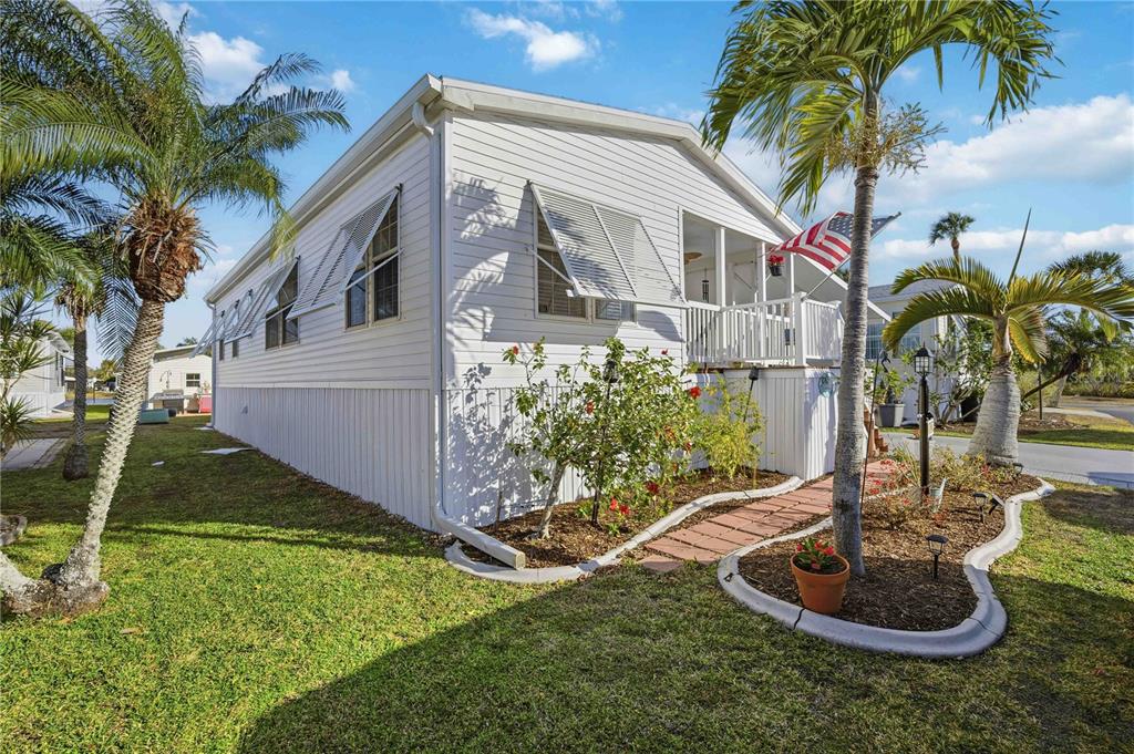 A white mobile home with a screened porch, palm trees, and a landscaped front yard — 10303 BURNT STORE ROAD UNIT 97, PUNTA GORDA, FL