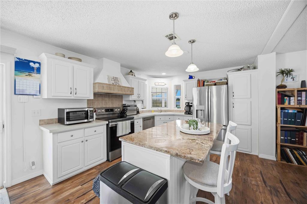 A kitchen with white cabinets, granite countertops, a center island, and stainless steel appliances — 10303 BURNT STORE ROAD UNIT 97, PUNTA GORDA, FL