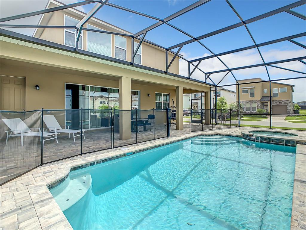 A screened-in swimming pool and spa with a patio and lounge chairs behind the house — 8919 TROPICAL HAVEN COURT, KISSIMMEE, FL