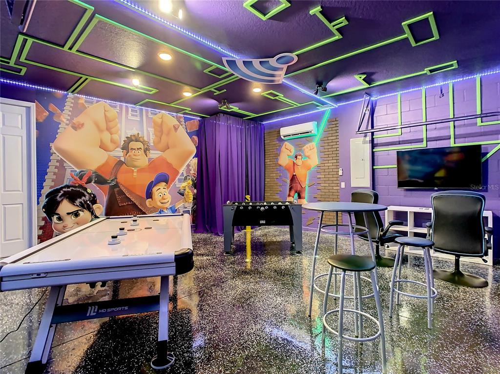 A game room features an air hockey table, foosball table, and Wreck-It Ralph wall murals — 8919 TROPICAL HAVEN COURT, KISSIMMEE, FL