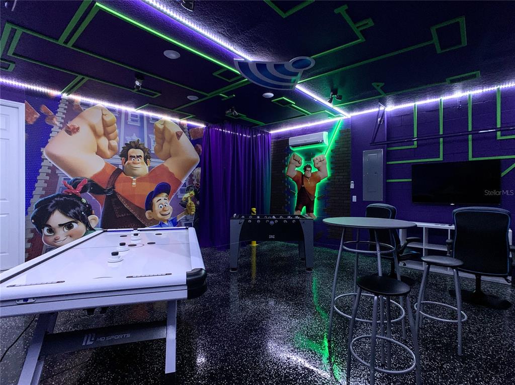 A Wreck-It Ralph themed game room features an air hockey table, foosball table, and neon lighting — 8919 TROPICAL HAVEN COURT, KISSIMMEE, FL