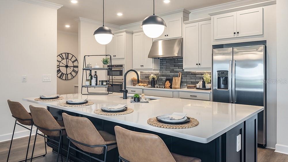 A modern kitchen features a large white island, dark cabinetry, and stainless steel appliances — 5412 GUNWALE DRIVE, COCOA, FL