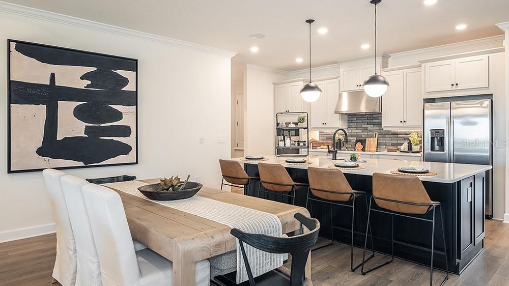 A dining area and kitchen feature a wooden table, black island, and white cabinetry — 5412 GUNWALE DRIVE, COCOA, FL