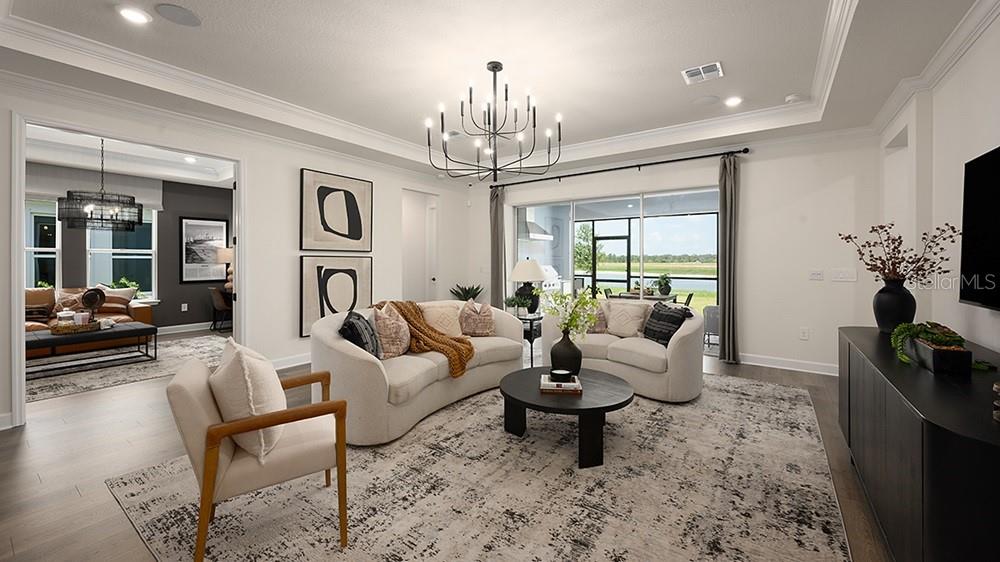 A bright living room features a curved sofa, round coffee table, and large sliding glass doors — 5412 GUNWALE DRIVE, COCOA, FL