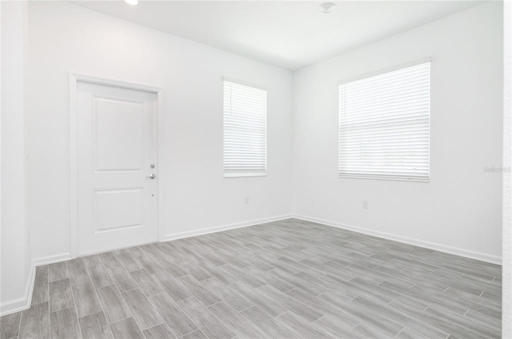 An empty room with white walls, gray wood-look tile flooring, and two windows with blinds — 6346 LIMBERPINE ALLEY, ST CLOUD, FL