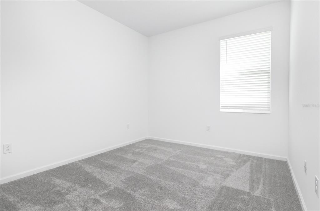 An empty bedroom features white walls, gray carpeting, and a single window with blinds — 6346 LIMBERPINE ALLEY, ST CLOUD, FL